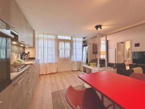 a kitchen and living room with a red table at Casa Aquila in Ringgenberg