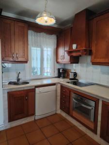 a kitchen with wooden cabinets and a white dishwasher at Casa Paloma Blanca in Málaga