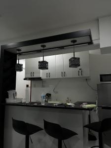 a kitchen with white cabinets and black stools at Mamitas Place, Royal Oceancrest Mactan in Lapu Lapu City