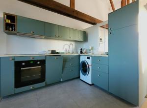 eine Küche mit blauen Schränken und einer Waschmaschine in der Unterkunft La petite bulle - Les Gîtes de la Côte d'Amour in Le Croisic
