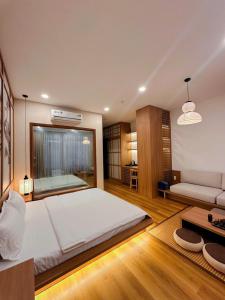 a bedroom with a large white bed and a couch at Katoya Suites Saigon Honkan 加藤部屋西貢本館 in Ho Chi Minh City