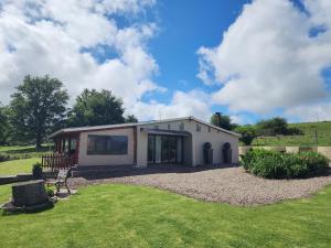 a small house in a field with a yard at Hogsback Misty Oaks Cottage in Hogsback