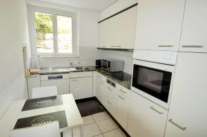 a white kitchen with white appliances and a window at Casa Carmela in Solothurn