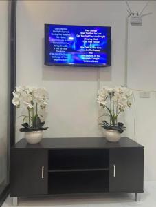 two vases with white flowers on a black cabinet at Mamitas Place, Royal Oceancrest Mactan in Lapu Lapu City