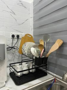 a kitchen counter with a shelf with utensils on it at AF Barokah Homestay Unit 1, Kuala Terengganu in Kuala Terengganu