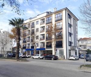 a large white building with cars parked in front of it at Sevez Apartments & Homes in Gelibolu