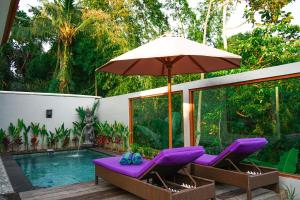 a patio with purple chairs and an umbrella and a pool at HOKYY Accommodation in Ubud