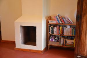 a living room with a fireplace and a book shelf with books at Milemeleni Guesthouse in Lushoto