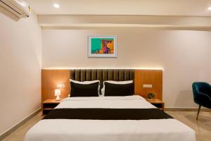 a bedroom with a large bed and a blue chair at Super Townhouse Lotus Grand in Hyderabad +28 photos