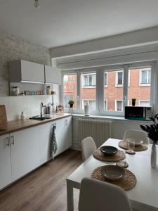 a kitchen with white cabinets and a table with chairs at Appartement cosy en centre ville de Dunkerque avec balcon & parking avec portail privé - place non nominative in Dunkerque