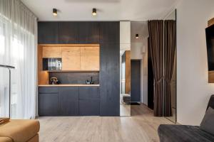 a kitchen with dark wood cabinets and a living room at Cozy Palanga Apartment in Palanga +10 photos