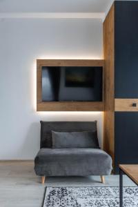 a living room with a couch and a tv on a wall at Cozy Palanga Apartment in Palanga