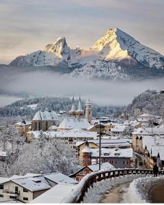 een besneeuwde stad met een berg op de achtergrond bij Fewo Auszeit am Königssee in Schönau am Königssee