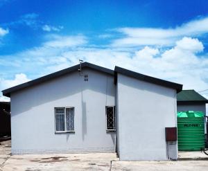 a white building with a green dumpster next to it at Crescent accommodation in Klerksdorp