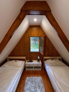a attic room with two beds and a window at Kerekerdő Apartman - Szarvaskő in Szarvaskő