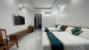 a hotel room with two beds and a flat screen tv at Bach Dai Dung Hotel 2 in Ha Tinh