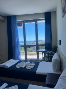 a bedroom with two beds and a large window at Afrodita Hotel in Sinemorets