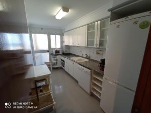 a kitchen with white cabinets and a white refrigerator at La Goleta Solo Familias Serviplaya in Playa de Xeraco +25 photos
