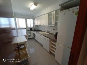 a kitchen with white cabinets and a white refrigerator at La Goleta Solo Familias Serviplaya in Playa de Xeraco