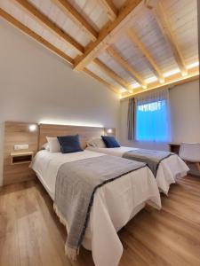 two beds in a bedroom with wooden ceilings at Apartamentos Las Terrazas de Suances in Suances