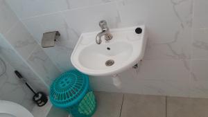 a white sink in a bathroom with a trash can at MJ homes in Mtwapa