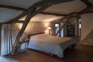 a bedroom with a bed in a room with wooden beams at Le pressoir du prieuré in Ligré
