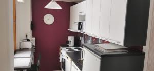 a kitchen with white cabinets and a red wall at Cozy Nilsiä Apartment in Nilsiä