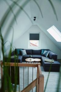 a living room with a blue couch and a table at Ferienwohnung KÖÖK Küstentraum - Modern, Balkon, Strandnah, Maisonette in Neuharlingersiel