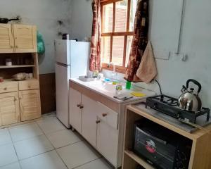 a small kitchen with a sink and a refrigerator at Cabaña Faro di luce in Santa Vitória do Palmar