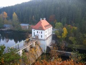 a large white building with a red roof on a river at Ferienwohnung Sonja in Prackenbach