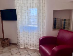 a living room with a red chair and a window at Villa Colle dei Trulli Monopoli in Monopoli