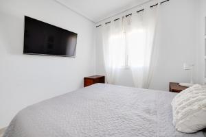 biała sypialnia z łóżkiem i telewizorem z płaskim ekranem w obiekcie CB Living - Cozy condo with patio, Playa Flamenca w mieście Orihuela Costa +20 zdjęć