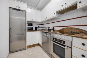 kuchnia z białymi szafkami i urządzeniami ze stali nierdzewnej w obiekcie CB Living - Cozy condo with patio, Playa Flamenca w mieście Orihuela Costa