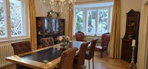 ein Esszimmer mit Tisch und Stühlen und Fenstern in der Unterkunft Ferienhaus Sanssouci in Stahnsdorf