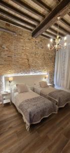 two beds in a room with a brick wall at Le camere di Rigoletto B&B in Parma
