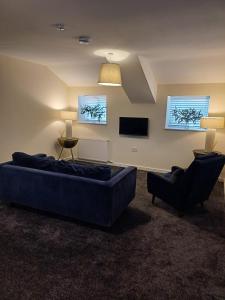 a living room with a large blue couch and two chairs at The Retreat Holywell in Holywell