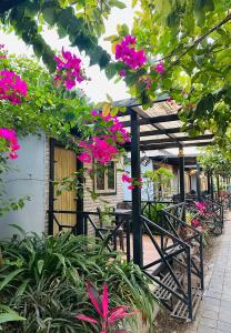 a patio with pink flowers and a wooden pergola at Raghunandan Resort Cottages in Nashik