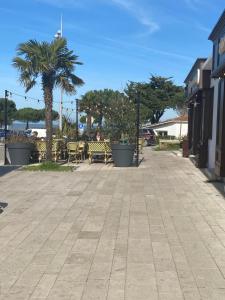 un trottoir avec des tables et des chaises et un palmier dans l'établissement La Maison du Clocher, à Rivedoux-Plage 10 autres photos