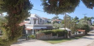 a white house with a fence in front of it at Vila 650 sqm, with Private Pool, 10 bedrooms with ensuite bathrooms & kitchen to each room - Elia Village by Irida Iris Group in Plomarion