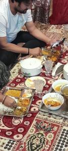 two people sitting on the floor with plates of food at Nature's Resort in Srinagar