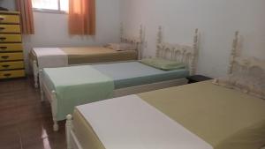 a group of four beds in a room at Casa acolhedora e familiar in Campos dos Goytacazes