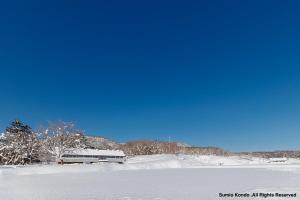 a snow covered field with a train in the background at Silent Cabin -dog friendly villa- in Nakagoya