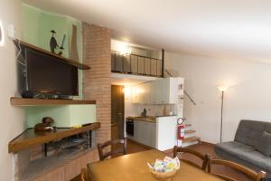 a kitchen and a living room with a table and a couch at SAILA Monolocale MARTE in Attigliano