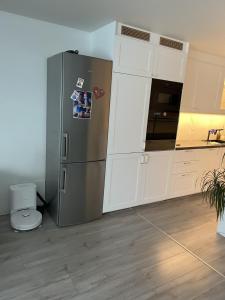 a kitchen with a stainless steel refrigerator and white cabinets at Trondheim in Trondheim +7 photos