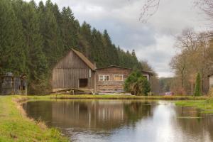a barn next to a pond with a house at Landgasthof Tönnes in Wipperfürth