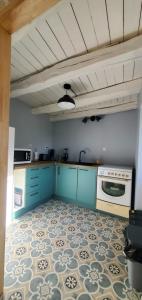 cocina con armarios azules y suelo de baldosa en Location petite maison, en Ambazac 10 fotos más