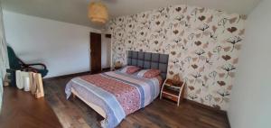Un dormitorio con una cama con papel pintado floral. en Location petite maison, en Ambazac