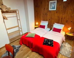 a bedroom with two beds with red sheets and a ladder at Superbe Chalet au calme, jardin et parking près de Paris in Fontenay-sous-Bois