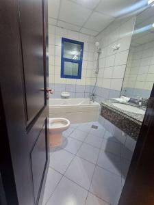 a bathroom with a tub and a toilet and a sink at Tabs Dubai Hostel in Dubai