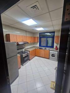 a kitchen with wooden cabinets and a white tile floor at Tabs Dubai Hostel in Dubai